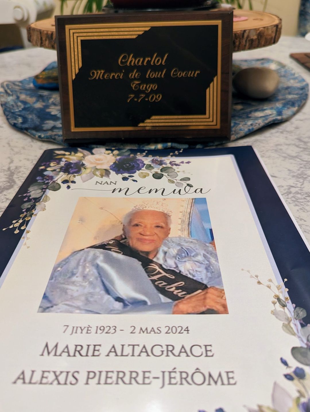 Poète et lodyansè Charlot Lucien exhibant une plaque d'appréciation que lui a décernée Altagrace Alexis Pierre-Jérôme pour ses travaux. « Bon voyage. Ta plaque est et restera dans mon bureau », écrit-il avec émotion sur Facebook.
)